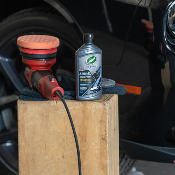 Turtle Wax Hybrid Solutions ceramic black polish & a buffer on wood. Car detailing products for paint correction and car care.