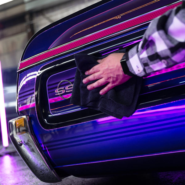 Detailing a classic car with a cloth. Polishing chrome and custom stripes on a blue SS vehicle. Automotive care.