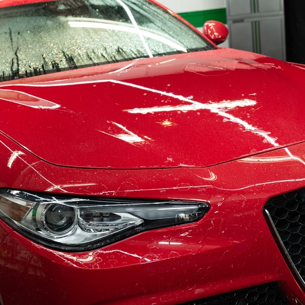 Shiny, red car hood after a wash. Water beading up on the wax finish. Car detailing.